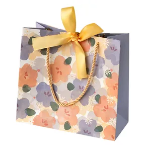 Bolsa de regalo festiva de papel con diseño floral de acuarela y lazo amarillo para cumpleaños