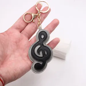 Bellissimo portachiavi in pelle con chiave di violino spessa e anelli dorati per borse e auto.