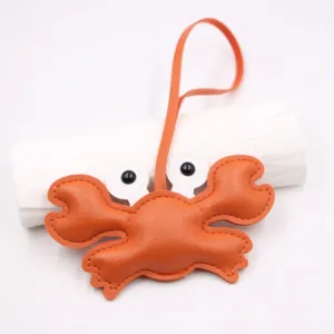 Orange leather crab bag charm detail, cute cartoon keychain pendant with white eyes.