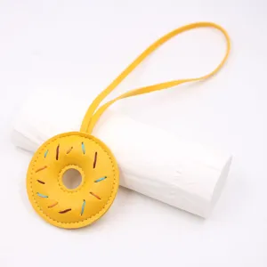 Λεπτομέρεια δερμάτινου donut charm χειροποίητη, με χρωματιστές ραφές και λουράκι.
