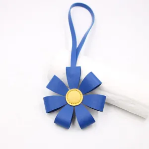 Detalle de colgante de bolso de margarita de cuero azul, centro amarillo vivo, llavero elegante.