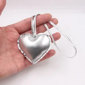 Silver heart leather bag charm detail showing glossy metallic finish and strap closeup.