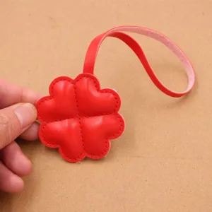 Pendentif de sac en cuir rouge trèfle à quatre feuilles lanière accessoire détail.