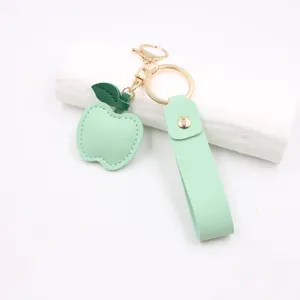 Detailed close-up of the green apple leather keychain with metal hardware and wrist strap.