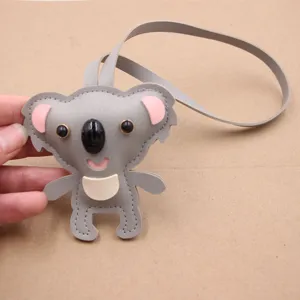 Cute grey koala leather bag charm detail, cartoon animal plush pendant close-up display.