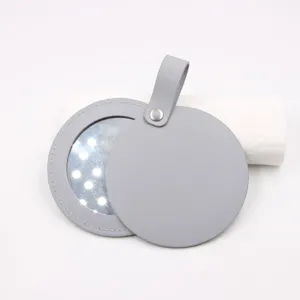Detail view of portable round leather makeup mirror with LED lights and hanging strap.