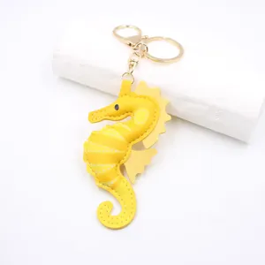 Yellow leather seahorse keychain and bag pendant with gold hardware and fine stitching.