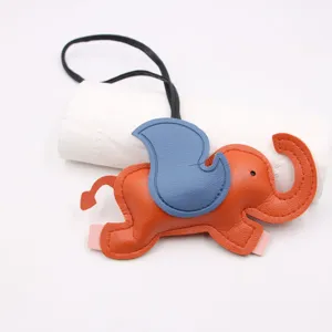 Detail closeup shot of a cute orange and blue leather elephant bag charm with black strap.