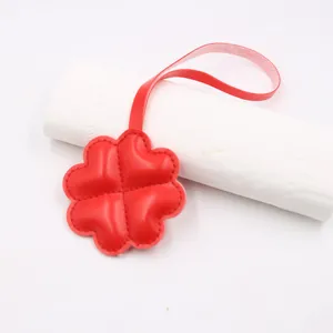 Pendentif de sac trèfle à quatre feuilles en cuir rouge accessoire pour vêtements et bagages.