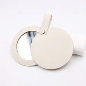 Portable round leather makeup mirror with hanging strap and snap button detail for handbags.