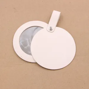 Close-up detail of the portable round leather makeup mirror, showing the chic beige charm design.