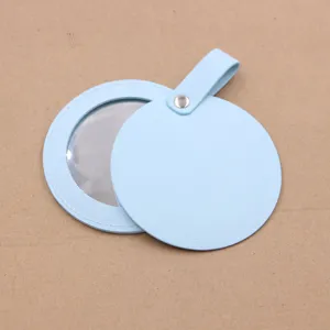 Portable blue leather round makeup mirror bag pendant detail view, compact travel cosmetic accessory.