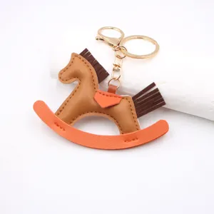 Leather rocking horse keychain bag charm with gold hardware and orange accent detailing.