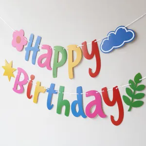 Colorful dopamine birthday banner detail, paper letter garland with cloud star cutouts.