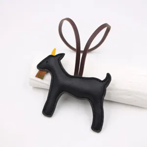 Leather goat bag charm detail, black leather purse pendant with brown strap and yellow horn.