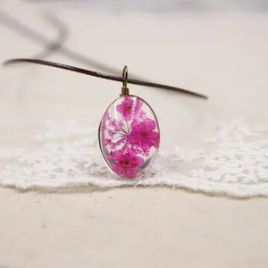 Collar con colgante de flor seca de resina ovalada hecho a mano, detalle de joyería floral.