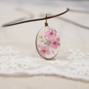 Collar de dije de flor seca resina ovalada hecho a mano vista de de detalle cercano