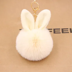 Fluffy bunny ear pompom keychain detail, soft faux fur texture with gold metal clasp hook.