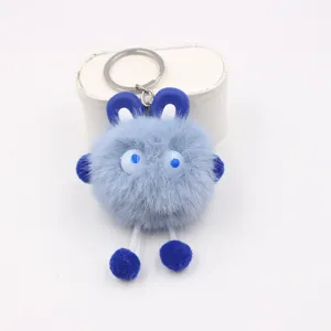 Close-up details of the fluffy blue plush keychain monster pendant with cute dangling feet.