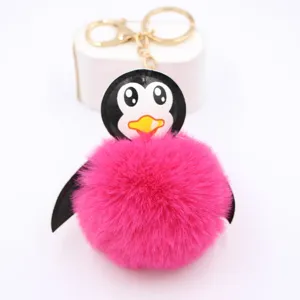 Dettaglio del portachiavi pompon in peluche pinguino con anello in metallo dorato.
