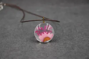 Preserved flower glass pendant necklace featuring pink daisy and dried floral in clear resin.