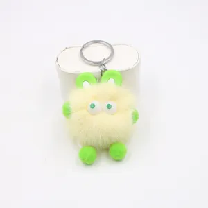 Close-up detail of the fluffy yellow plush bunny keychain featuring green ears and big eyes.