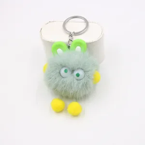 Close-up detail of the cute green plush toy keychain with fluffy ball and soft rabbit ears.