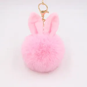 Cute pink rabbit ear plush pom pom keychain accessory for bags and keys, fluffy faux fur charm.
