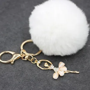 Detalle en primer plano del llavero pompón de felpa blanca esponjosa con colgante bailarina estrás.