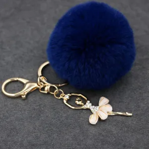 Primer plano del llavero con pompón de pelo sintético azul y colgante de ángel.