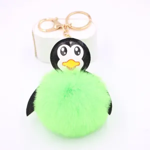 Dettaglio del portachiavi pinguino in peluche verde con pallina soffice e anello dorato.