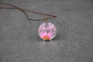 Exquisite preserved flower glass pendant necklace featuring delicate pink blossoms inside.