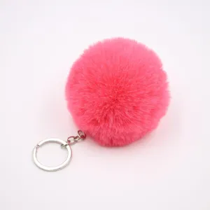 Pink faux fur pom pom keychain detail shot, fluffy ball pendant for bag and car key charm.