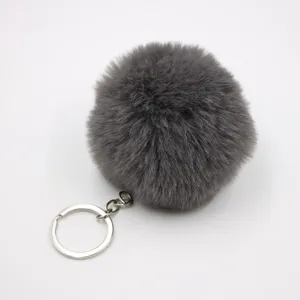 Grey fluffy plush pom pom keychain detailed view, soft faux fur bag charm and car pendant.