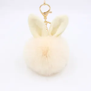 Plush rabbit ear pom pom keychain detail shot showing soft faux fur and gold clasp charm.