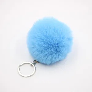 Close-up detail of fluffy blue faux rabbit fur pom pom keychain with metal ring pendant.