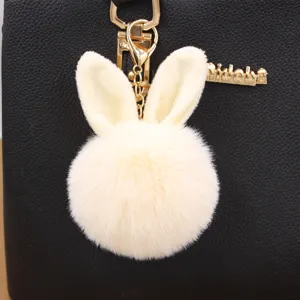 Cute rabbit ear plush pompom keychain detail view, soft faux fur bag charm accessory.