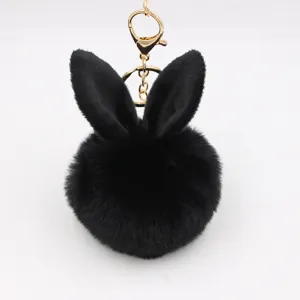 Close-up detail of the black plush bunny ear pom-pom keychain with gold hardware decoration.