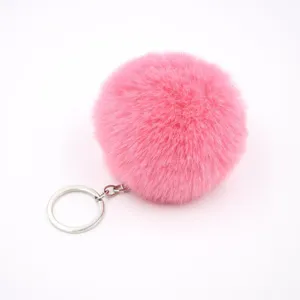 Close-up detail of soft fluffy pink faux fur pom pom keychain with silver metal ring.