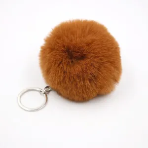 Brown fluffy pom pom keychain detail shot, soft faux rabbit fur pendant with silver keyring.