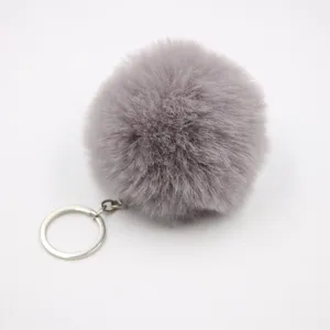 Close-up of fluffy grey faux rabbit fur pom pom keychain pendant, soft texture metal ring detail.