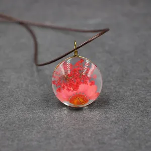Close-up detail shot of the handmade pressed dried flower resin round pendant necklace.