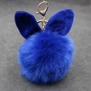 Blue faux fur pom pom keychain with cute plush bunny ears and gold metal clasp detail.