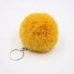Yellow fluffy faux rabbit fur pom pom keychain detail shot, cute bag charm pendant.