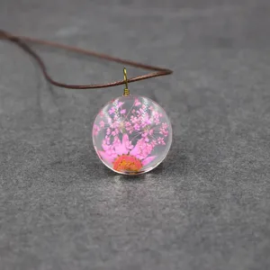 Exquisite pressed flower glass pendant necklace with pink dried daisies and cord chain detail.