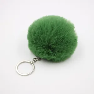 Green faux rabbit fur pom pom keychain detail view, fluffy ball pendant for bag and car.