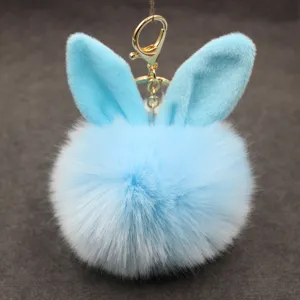 Close-up of fluffy blue rabbit ear faux fur pom pom keychain charm with gold metal clasp.