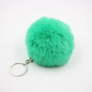 Close-up detail of the vibrant green fluffy faux fur pom-pom keychain with silver metal ring.