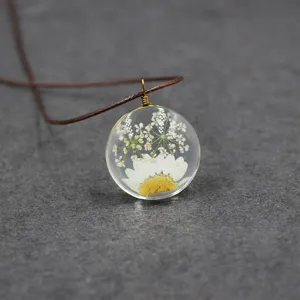 Pressed flower glass pendant necklace, handmade dried daisy resin jewelry detail close up.