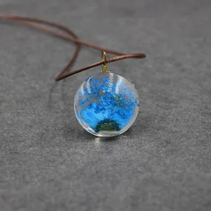 Resin dried flower pendant necklace close-up, handmade botanical jewelry with brown cord.